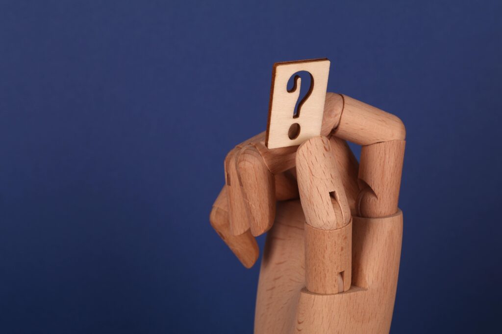 wooden hand holding a wooden question mark