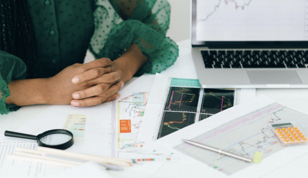 person sitting at a desk with their arms crossed, looking at financial charts